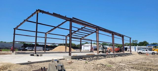 A large metal structure is being built in a dirt field.