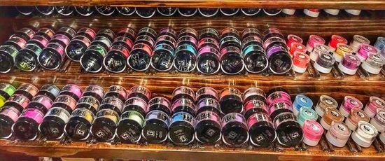A shelf filled with lots of different colored bottles.