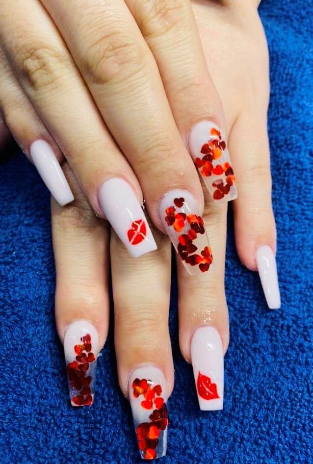 A close up of the nails of a woman with red hearts and kisses on them