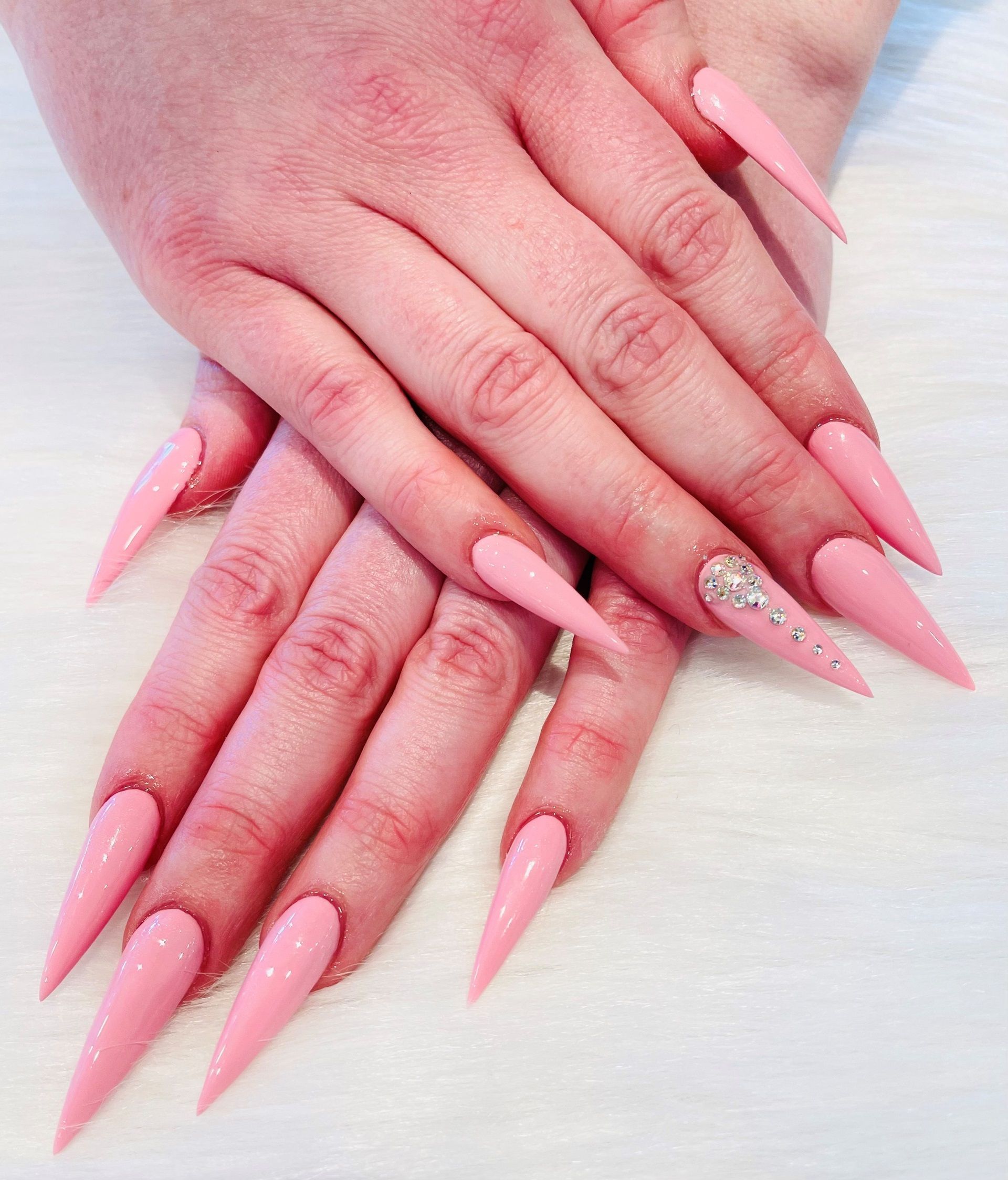 A close up of a woman's hands with long pink nails