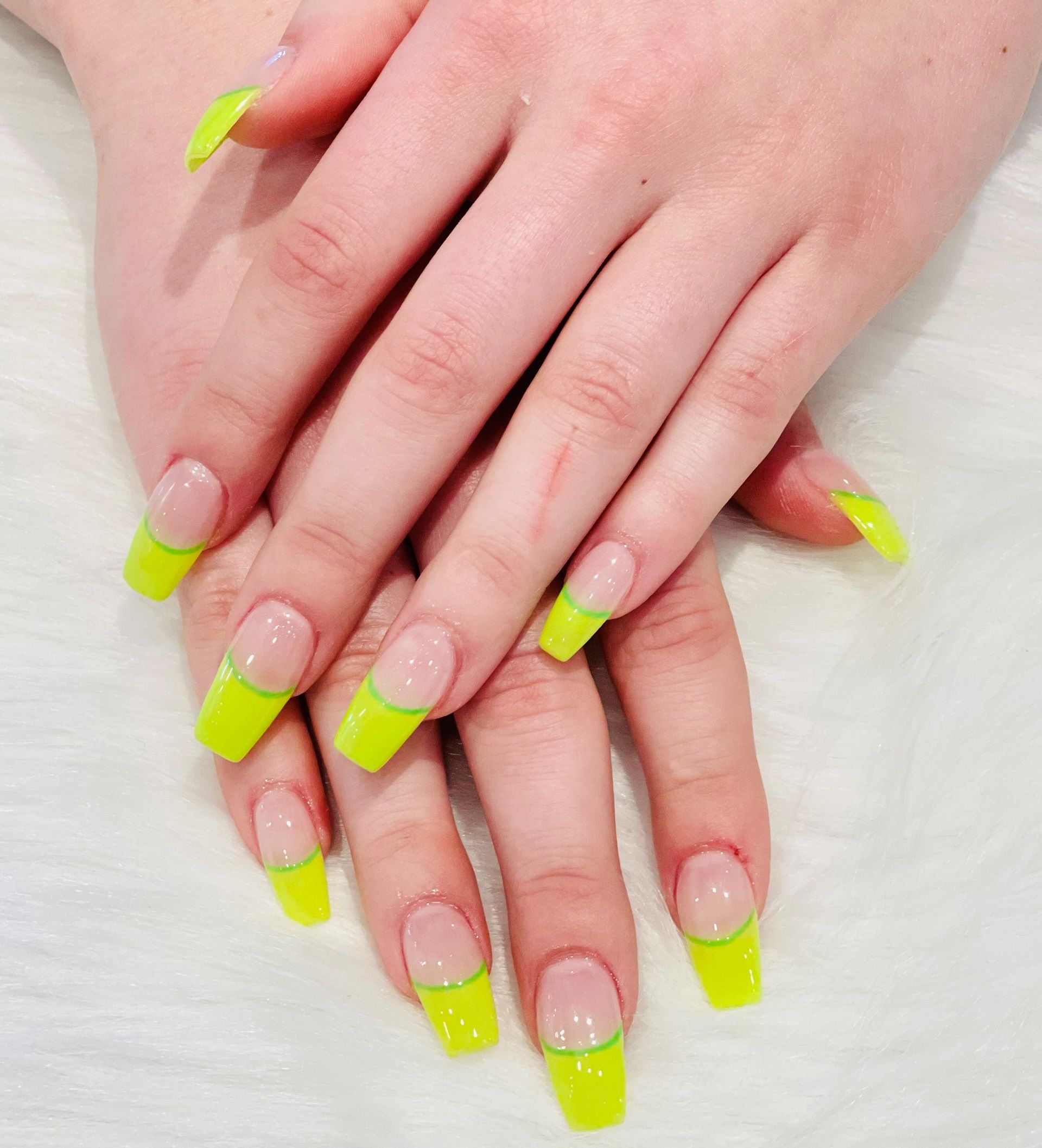 A close up of a woman's hands with neon yellow nail polish