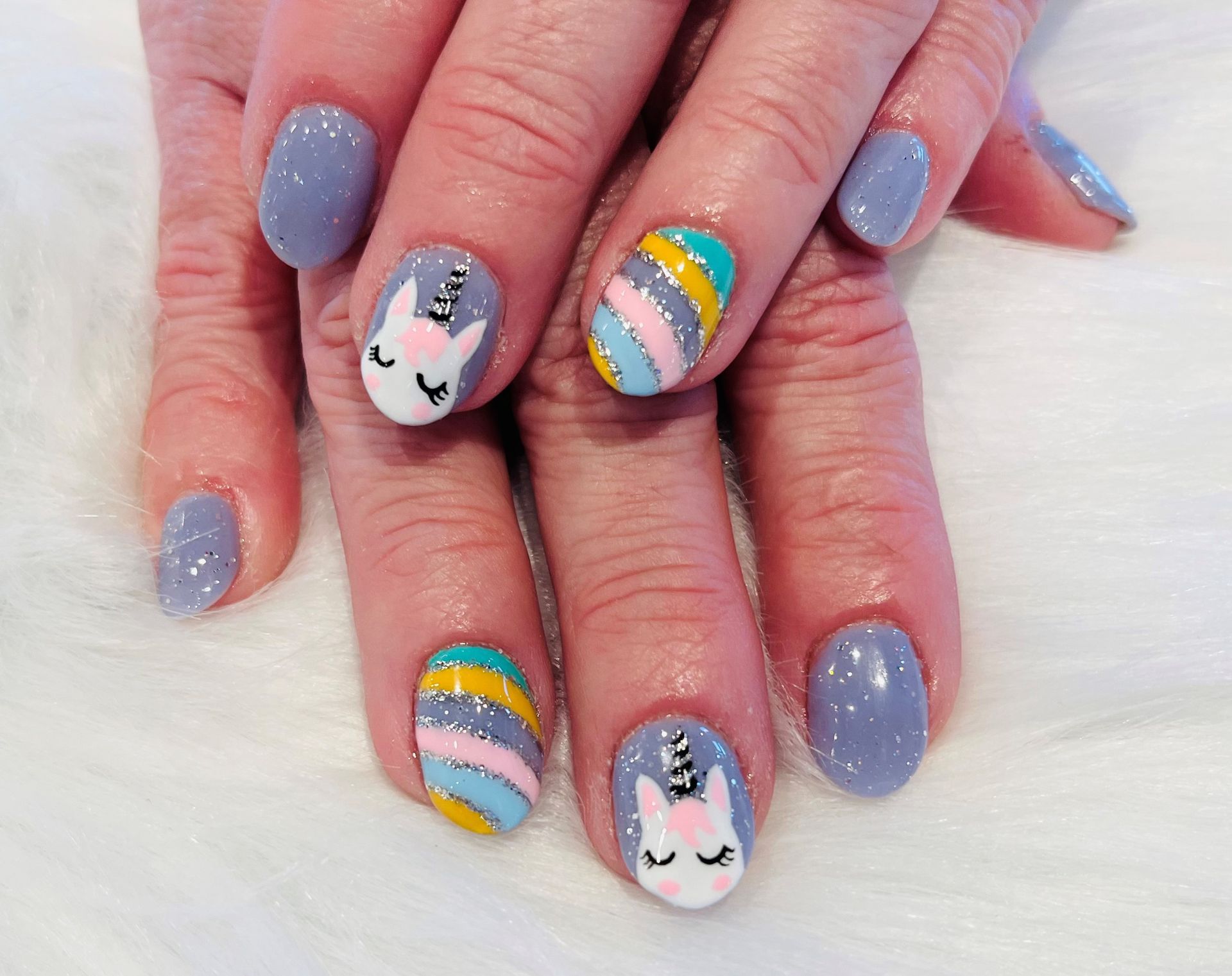 A close up of a person's nails with a unicorn design