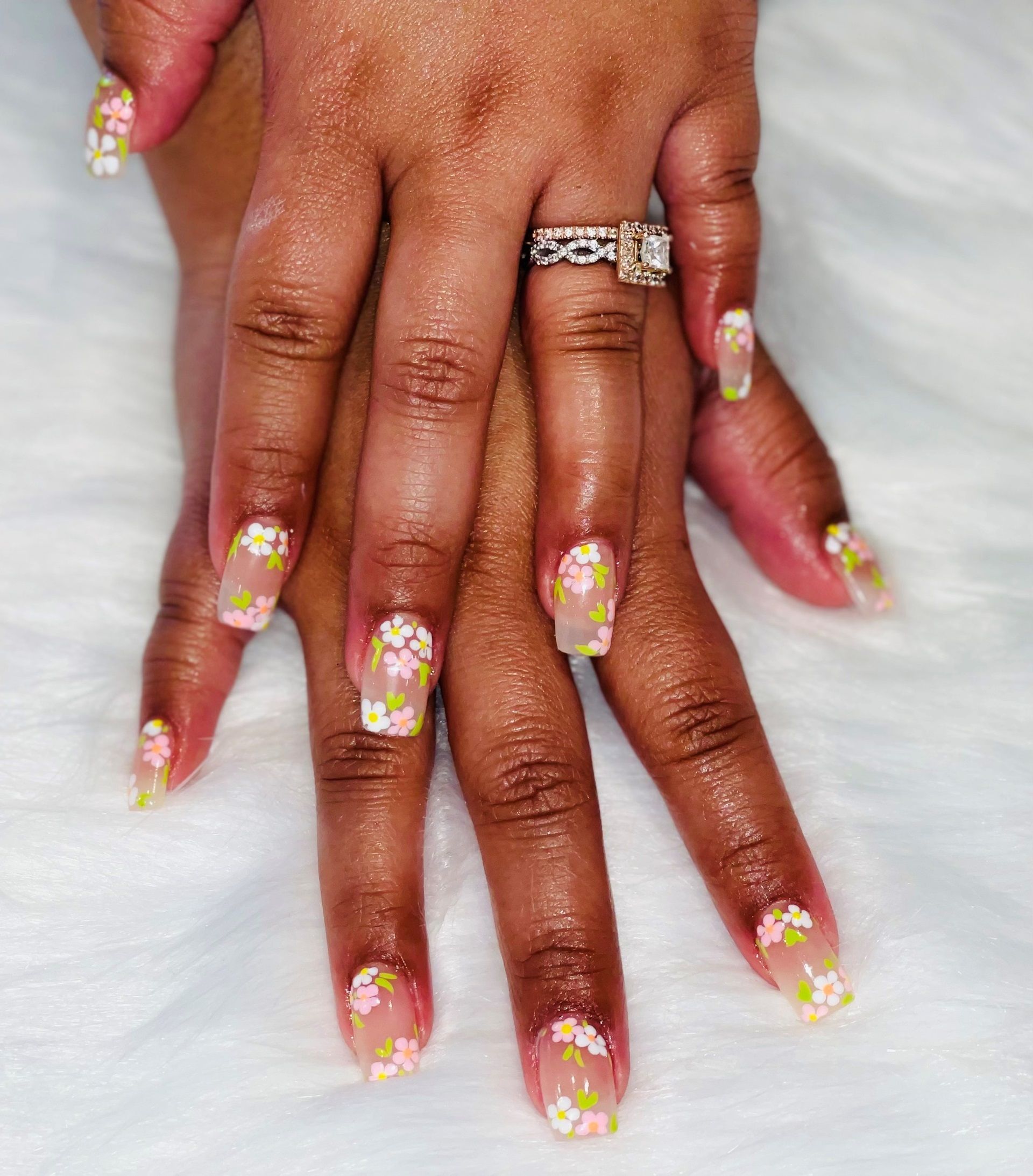 A close up of a woman's nails with white and pink flower nail design