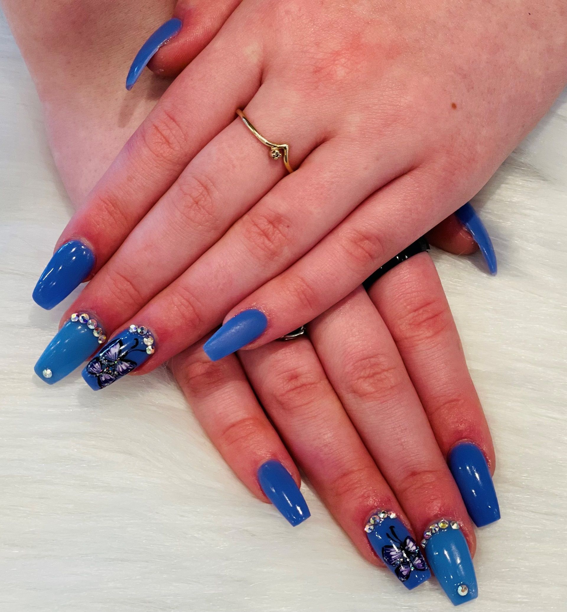 Hands of a woman with blue nails and a gold ring