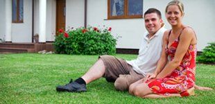 Couple sitting on lawn and enjoying their clean yard