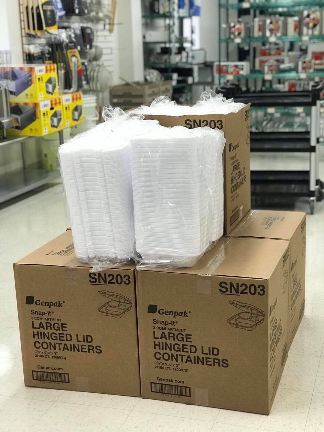 Boxes of hinged lid containers stacked in a store.