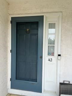 A blue and white front door with a screen door and a window.
