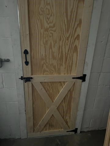 A wooden sliding barn door is sitting in a room next to a brick wall.