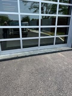 A car is reflected in the glass of a garage door.