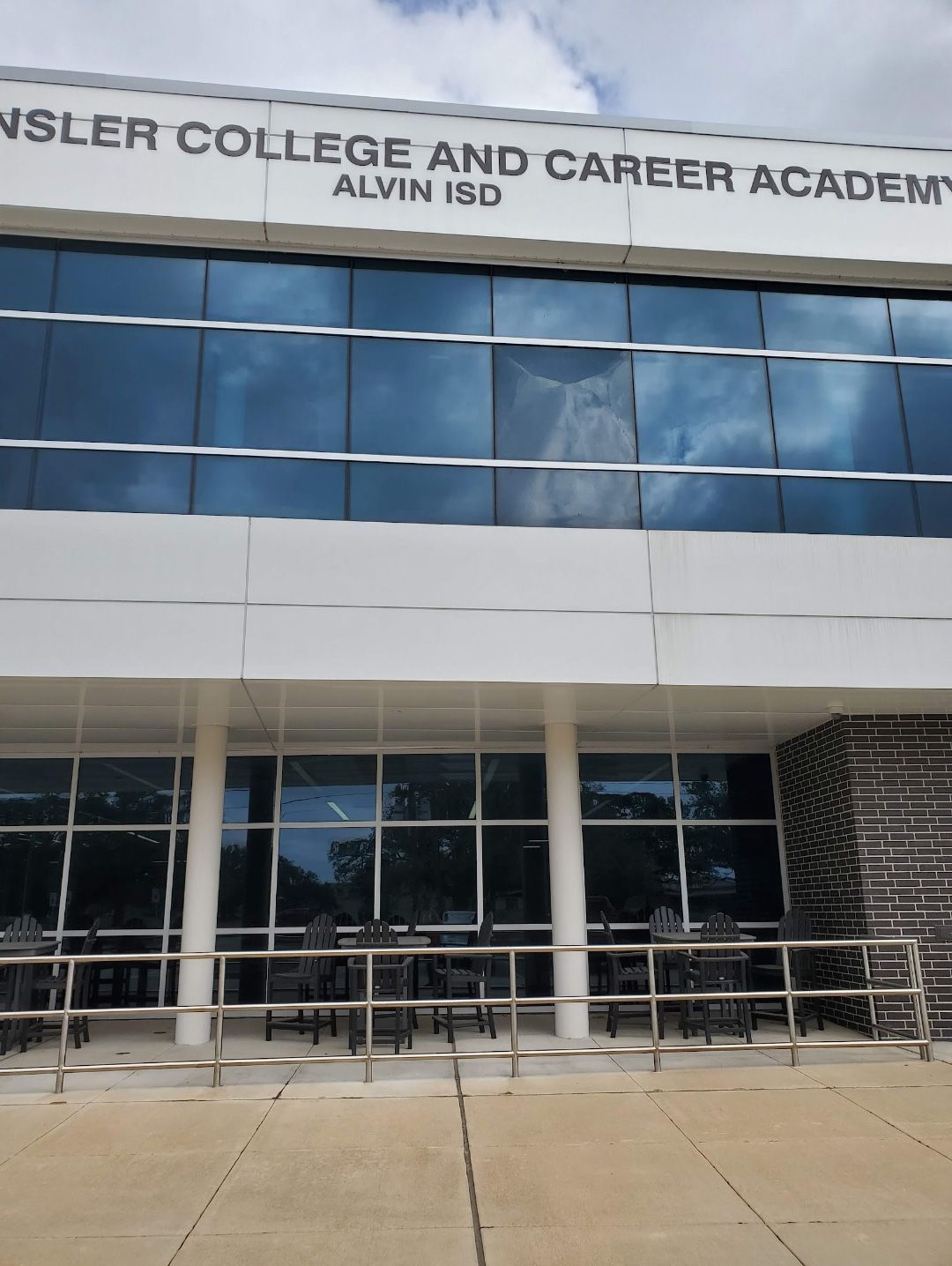 The exterior of the Hinsley College and Career Academy in Alvin ISD, featuring glass windows and white facade panels.