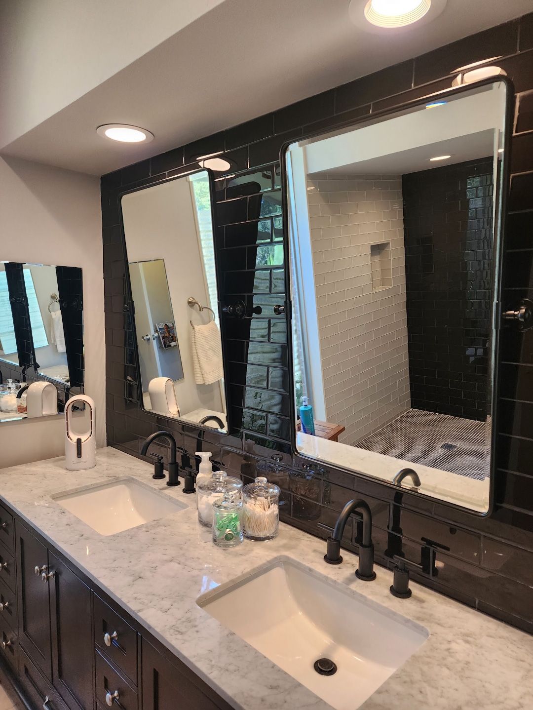A modern double-sink bathroom vanity with dark wood cabinets, marble countertops, and two rectangular mirrors on a wall.