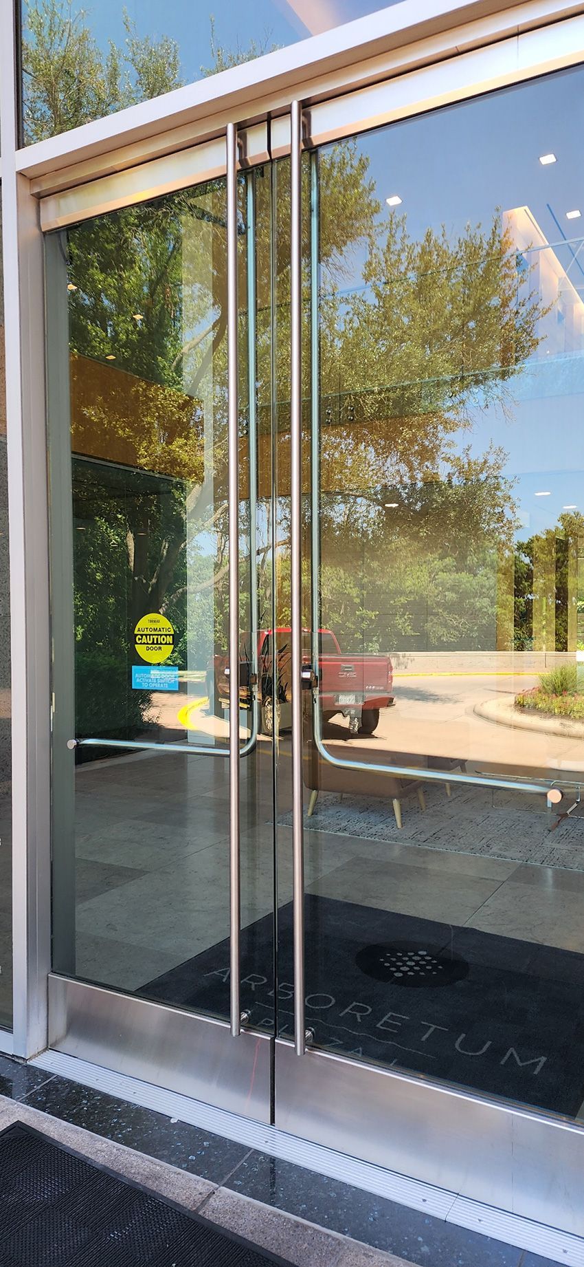 Two clear glass entrance doors with metal frames and horizontal push bars, viewed from the exterior.