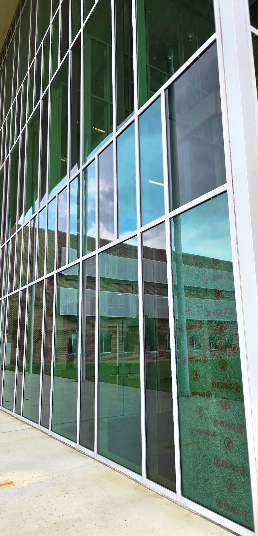 A modern, white, industrial-style commercial building with large glass windows, a dark roof, and a stone-tiled base.