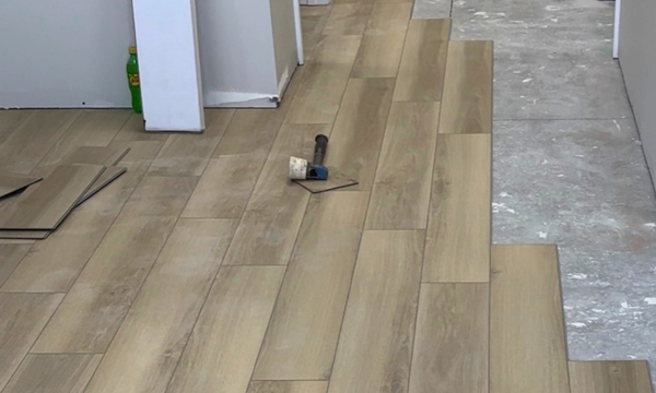 Wood-look flooring being installed in a room, with a small tool resting on the planks.