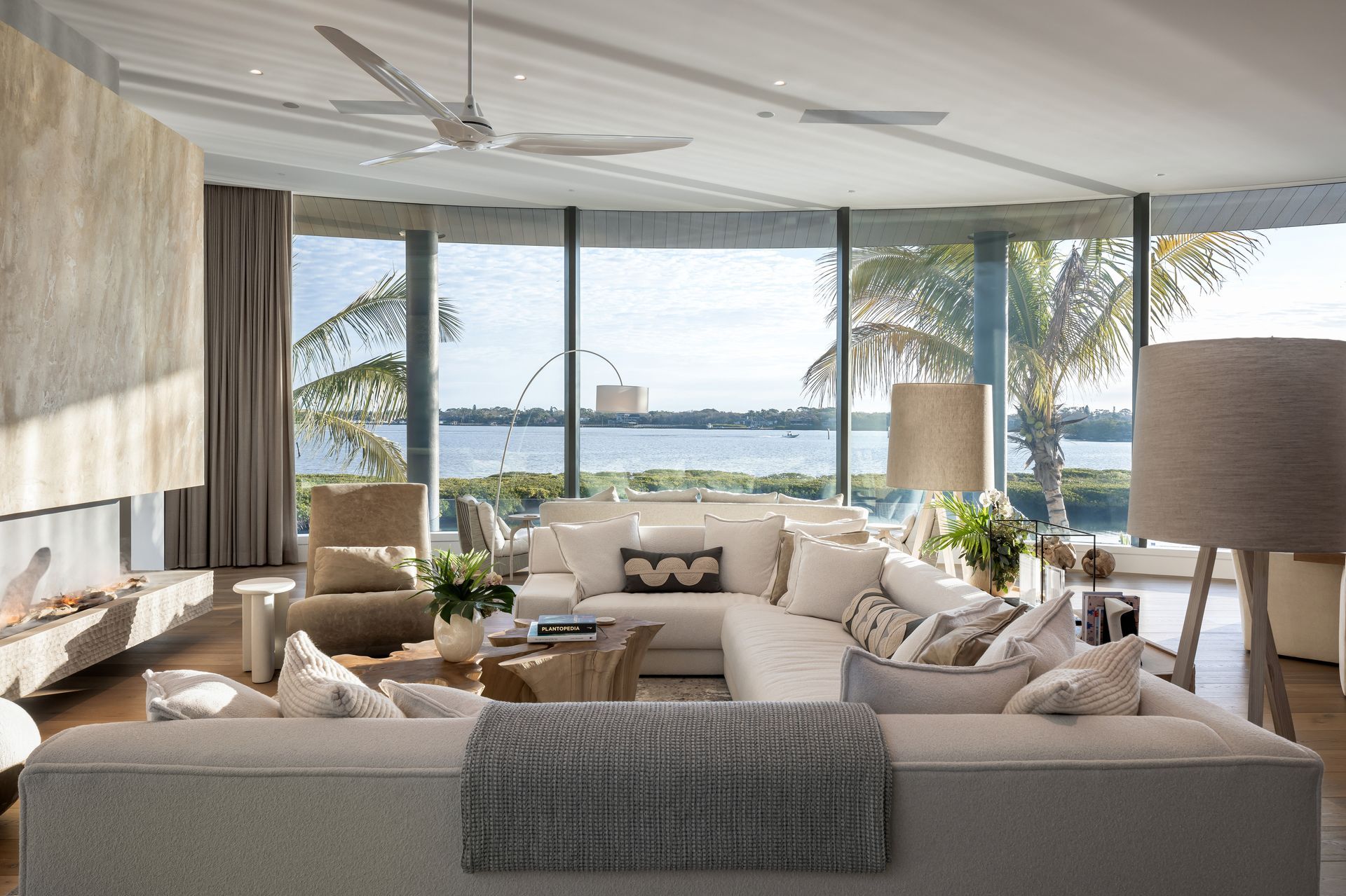 Spacious living room with waterfront view, white sectional sofa, neutral tones, and large windows.