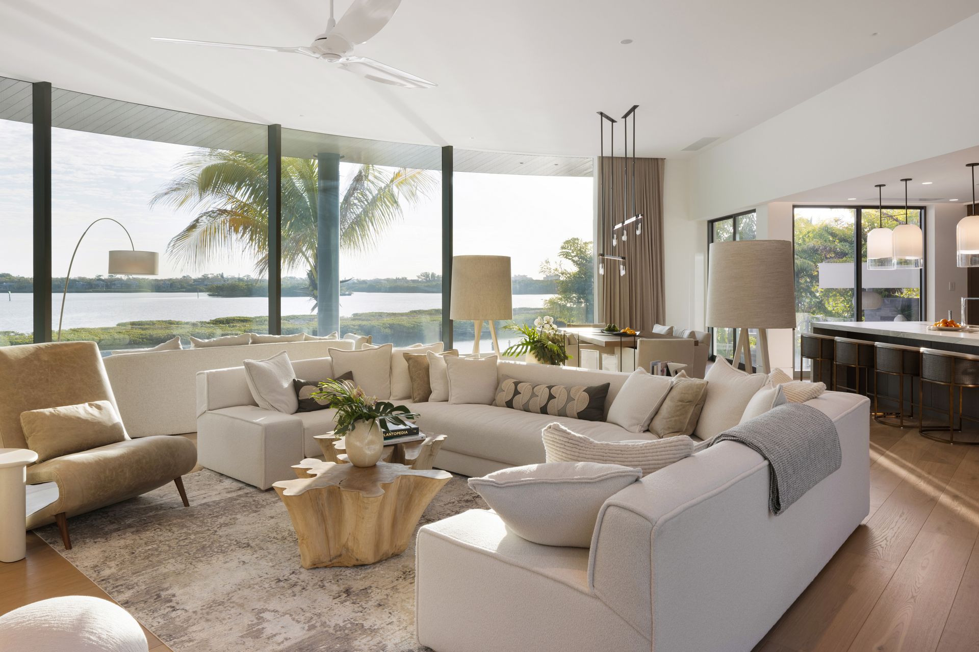Spacious living room with white sectional sofa, large windows overlooking water.