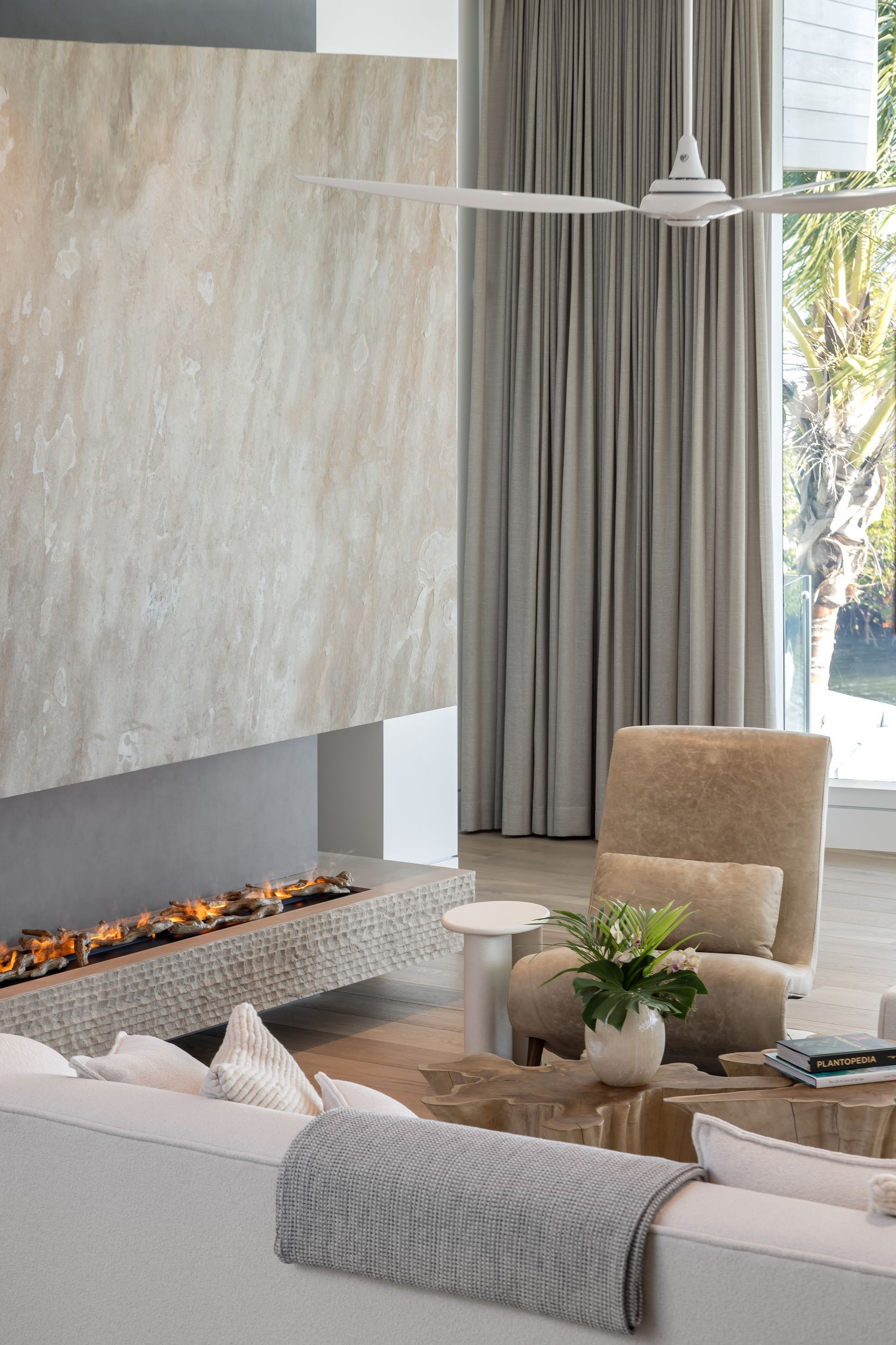 Modern living room with fireplace, white walls, and beige chair, near a window.