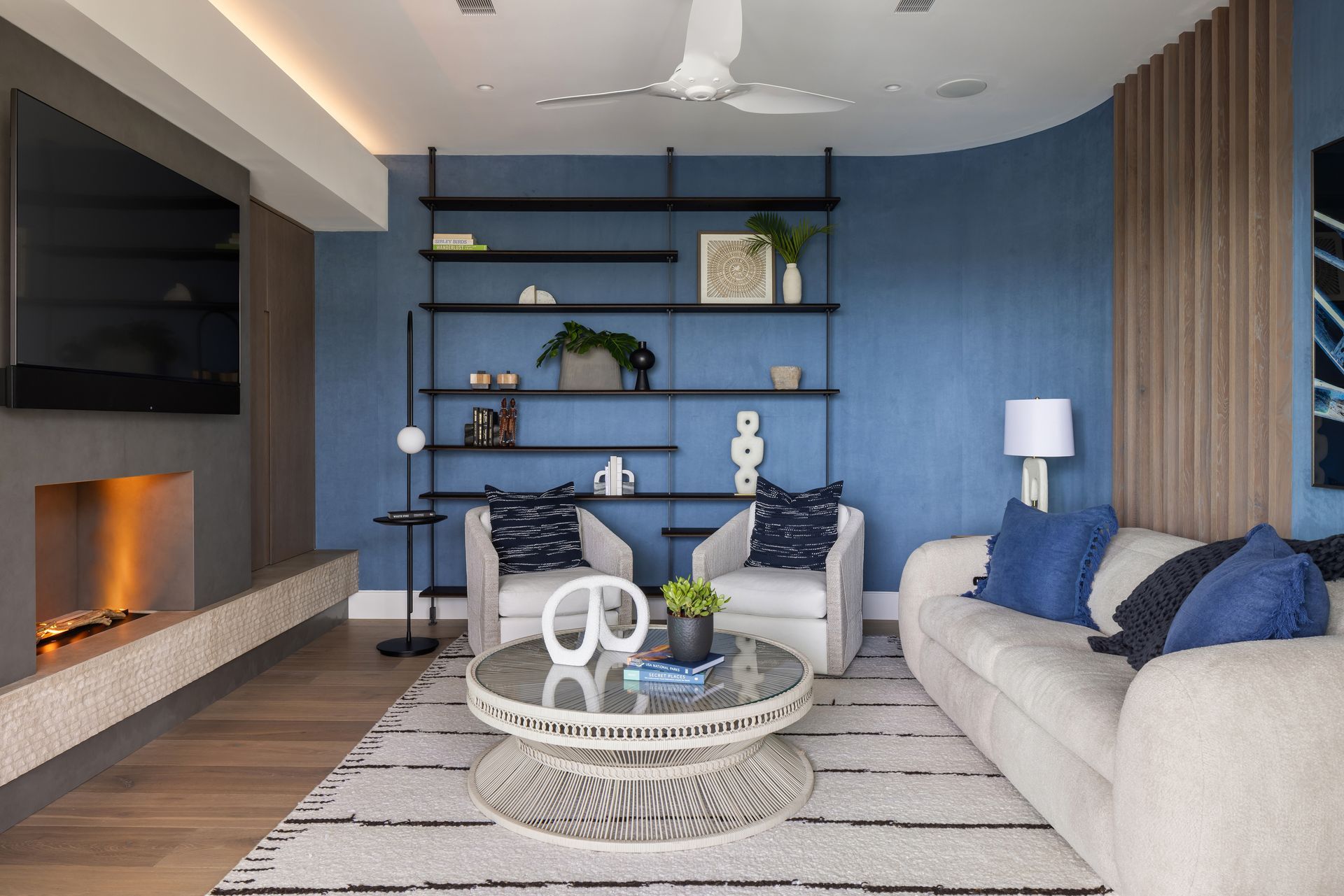 Modern living room with blue accent wall, fireplace, and white furniture.