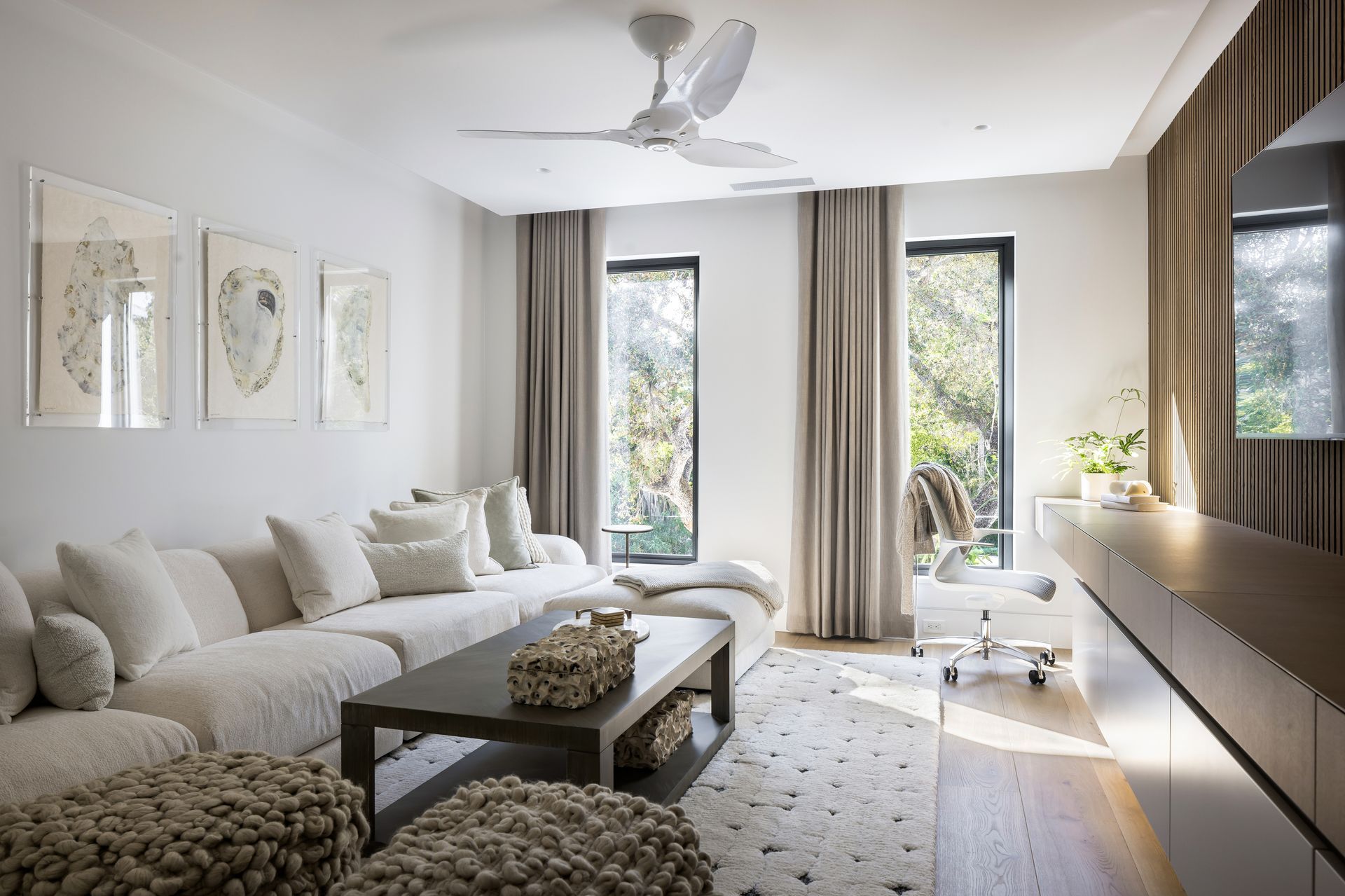Living room with white sectional sofa, three framed artworks, and a coffee table.