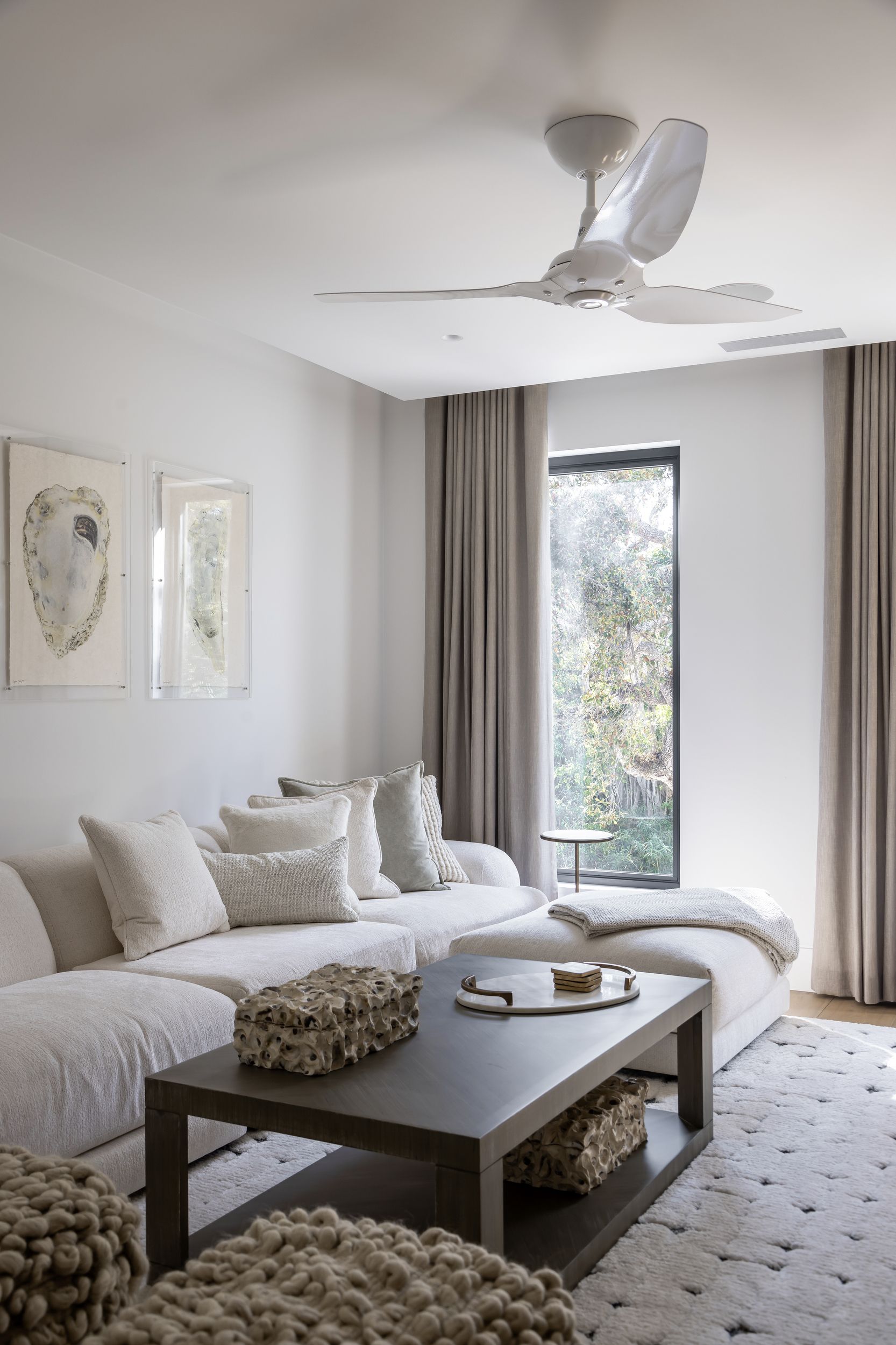 Cozy living room with white sectional sofa, art, and a coffee table, neutral tones.