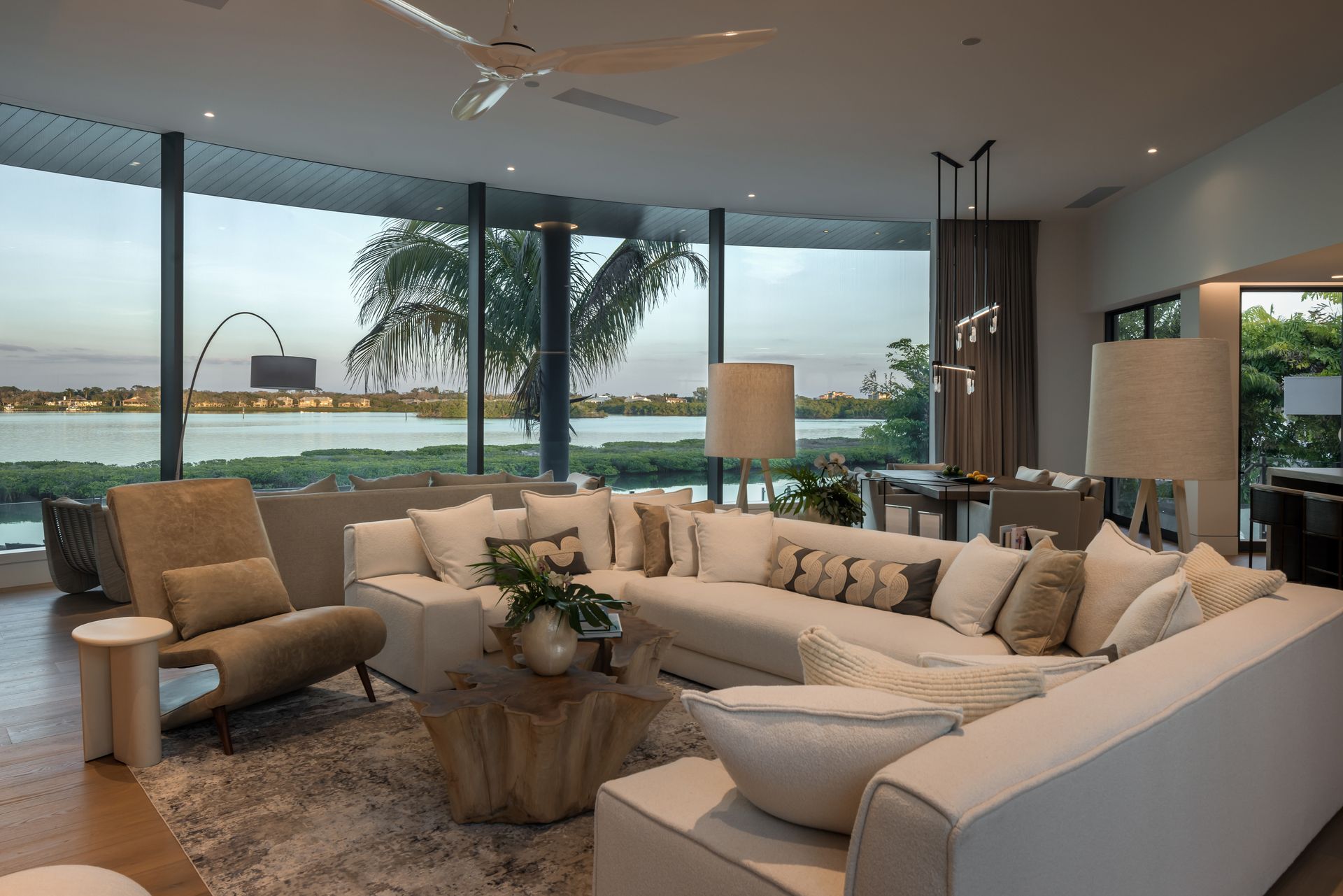 Modern living room with sectional sofa, large windows, and water view.