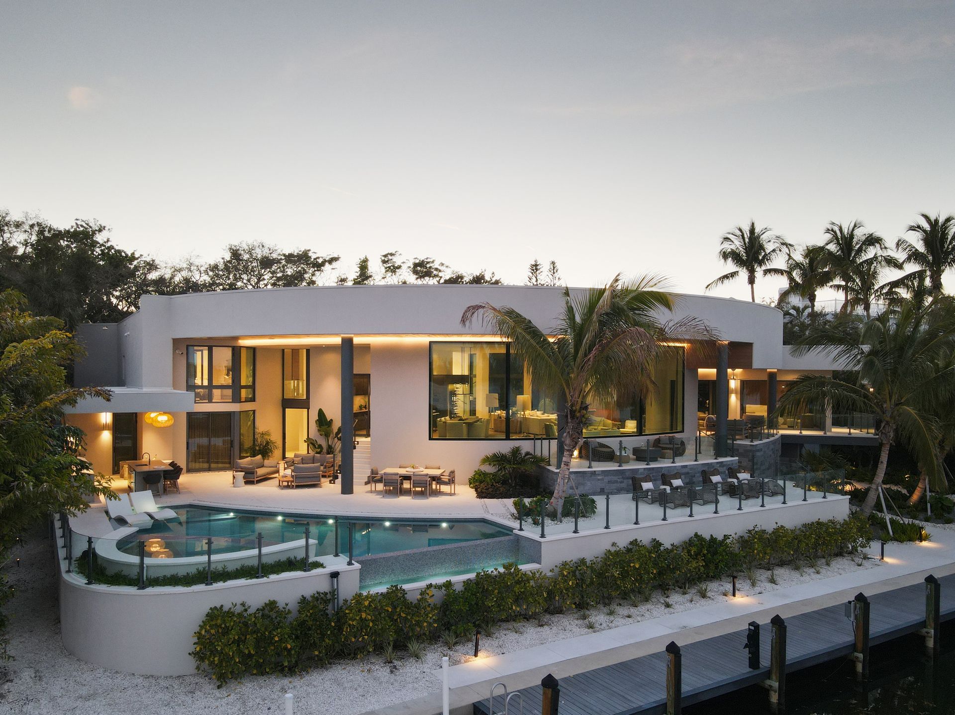 Modern waterfront house with pool and outdoor seating.