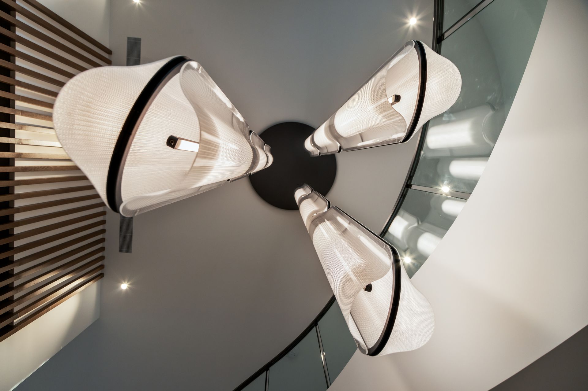 Three white, cone-shaped pendant lights with black trim are suspended from a black ceiling plate.