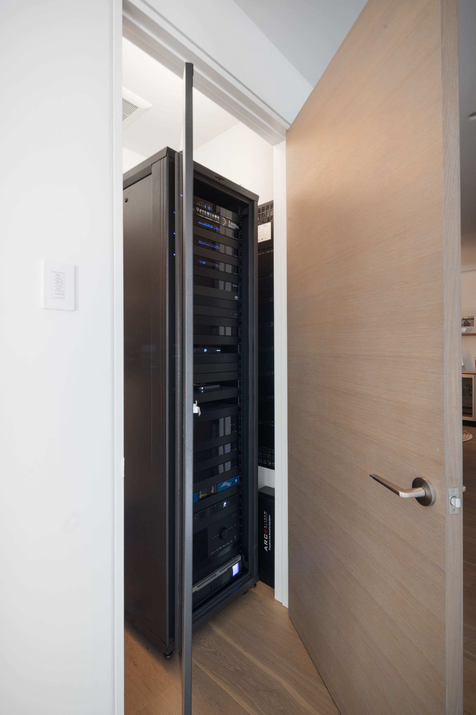 Server rack inside a closet with the door slightly open.
