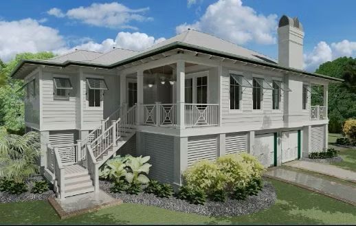 White two-story house with porch, shutters, and stairs. Landscaping in a sunny setting with blue sky.