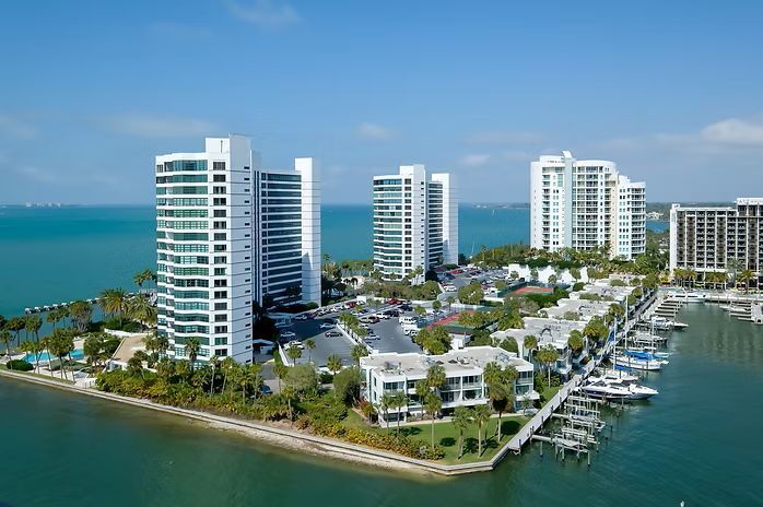 High-rise condos and boat docks on a waterfront, sunny day with blue sky and water.