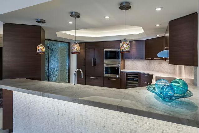 Modern kitchen with dark wood cabinets, light countertops, and pendant lights.