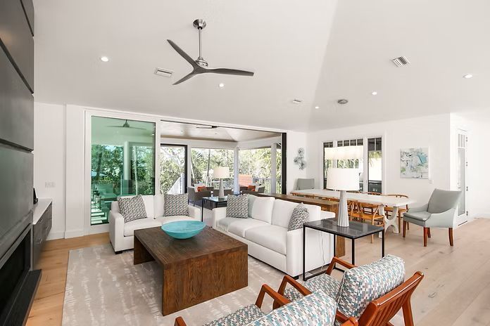 Bright living room with white sofas, wooden coffee table, and open to outdoor patio.