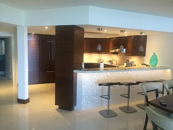Modern kitchen with dark wood cabinets, a tile-faced bar, and stainless steel stools.