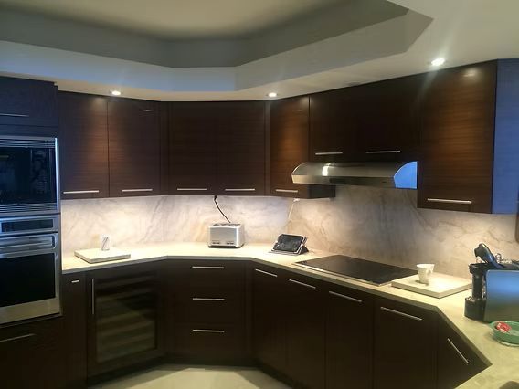 Dark wood kitchen cabinets with light countertops and under-cabinet lighting.