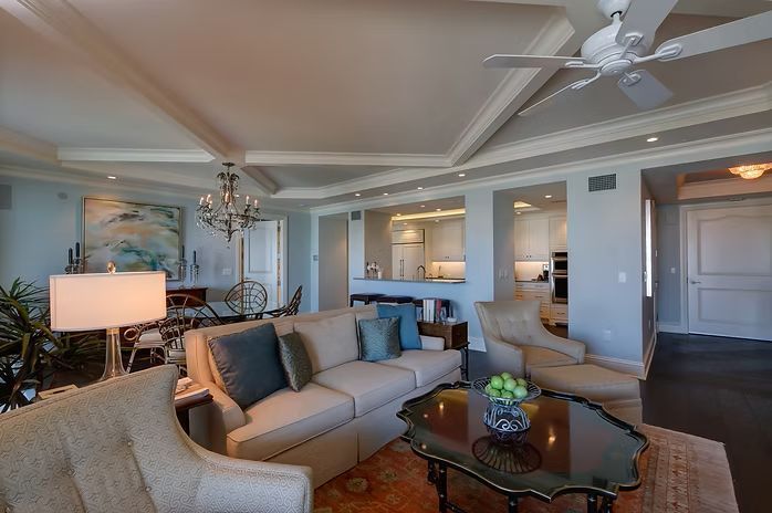 Living room with cream-colored couch, two armchairs, a coffee table, and a dining area.