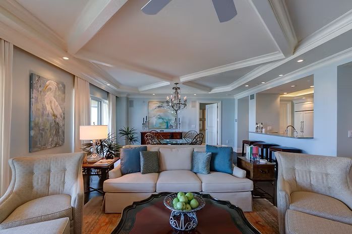 Living room with cream sofa, two armchairs, a dark wood coffee table, and blue pillows.