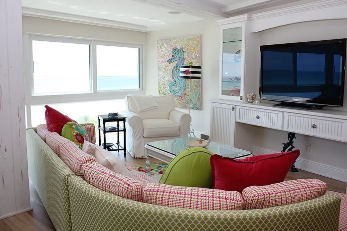 Living room with a curved sofa, seahorse artwork, and ocean view.
