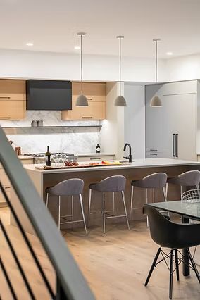 Modern kitchen with island seating, neutral tones, pendant lights, and stainless steel appliances.
