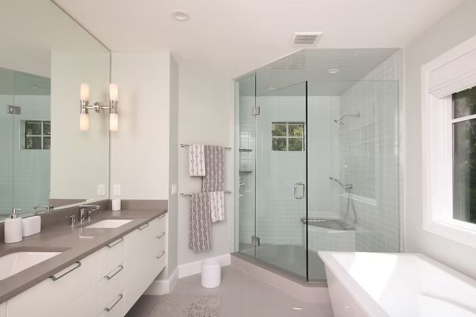 Modern bathroom with a glass shower, soaking tub, double vanity, and window.