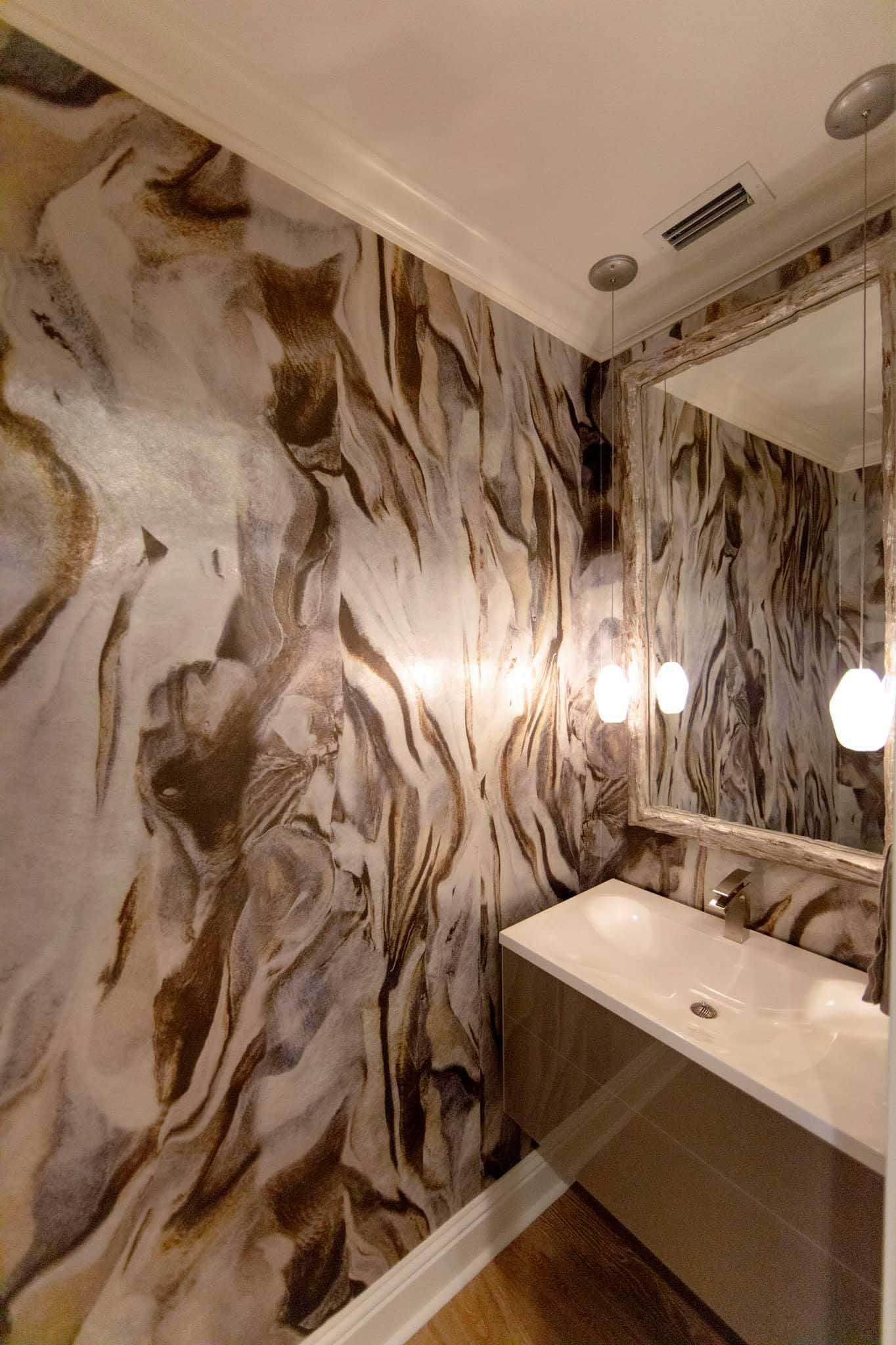 Powder room with marble-like patterned walls, floating sink, and a large mirror reflecting the space.
