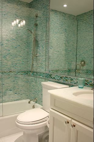 Bathroom with teal mosaic tile walls, a white toilet, sink, and bathtub.