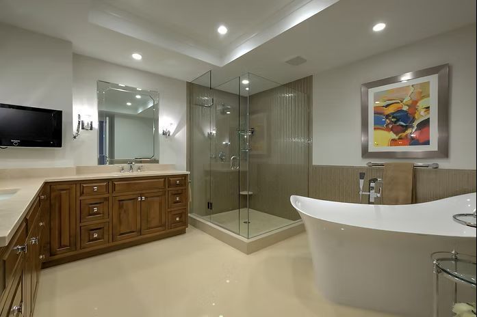 Luxurious bathroom with wood vanity, glass shower, freestanding tub, artwork, and a TV.