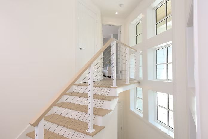 Staircase with light wood steps, white walls, and a window feature.