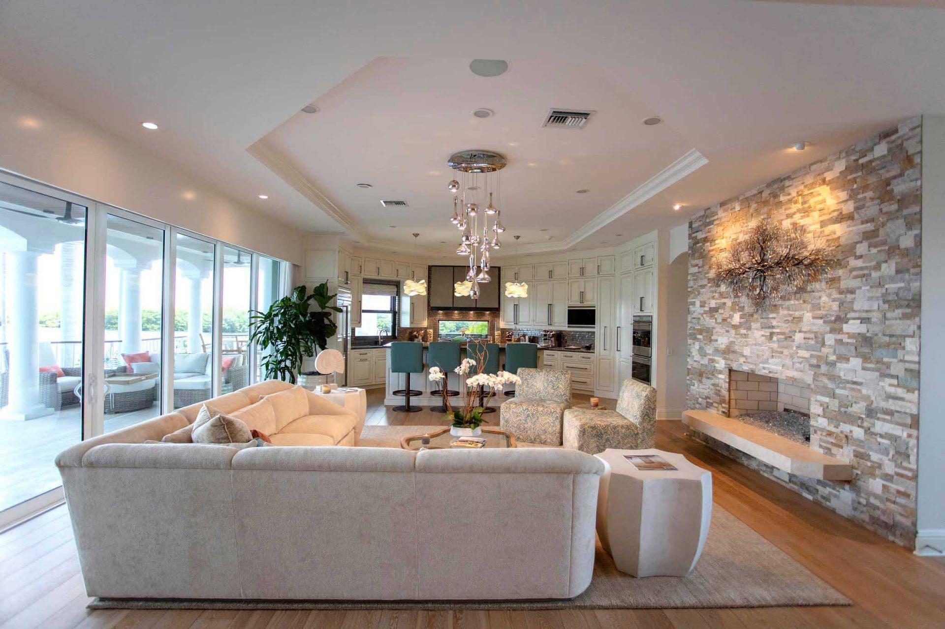 Spacious, light-filled living room with stone accent wall and modern furnishings, leading to an outdoor terrace.
