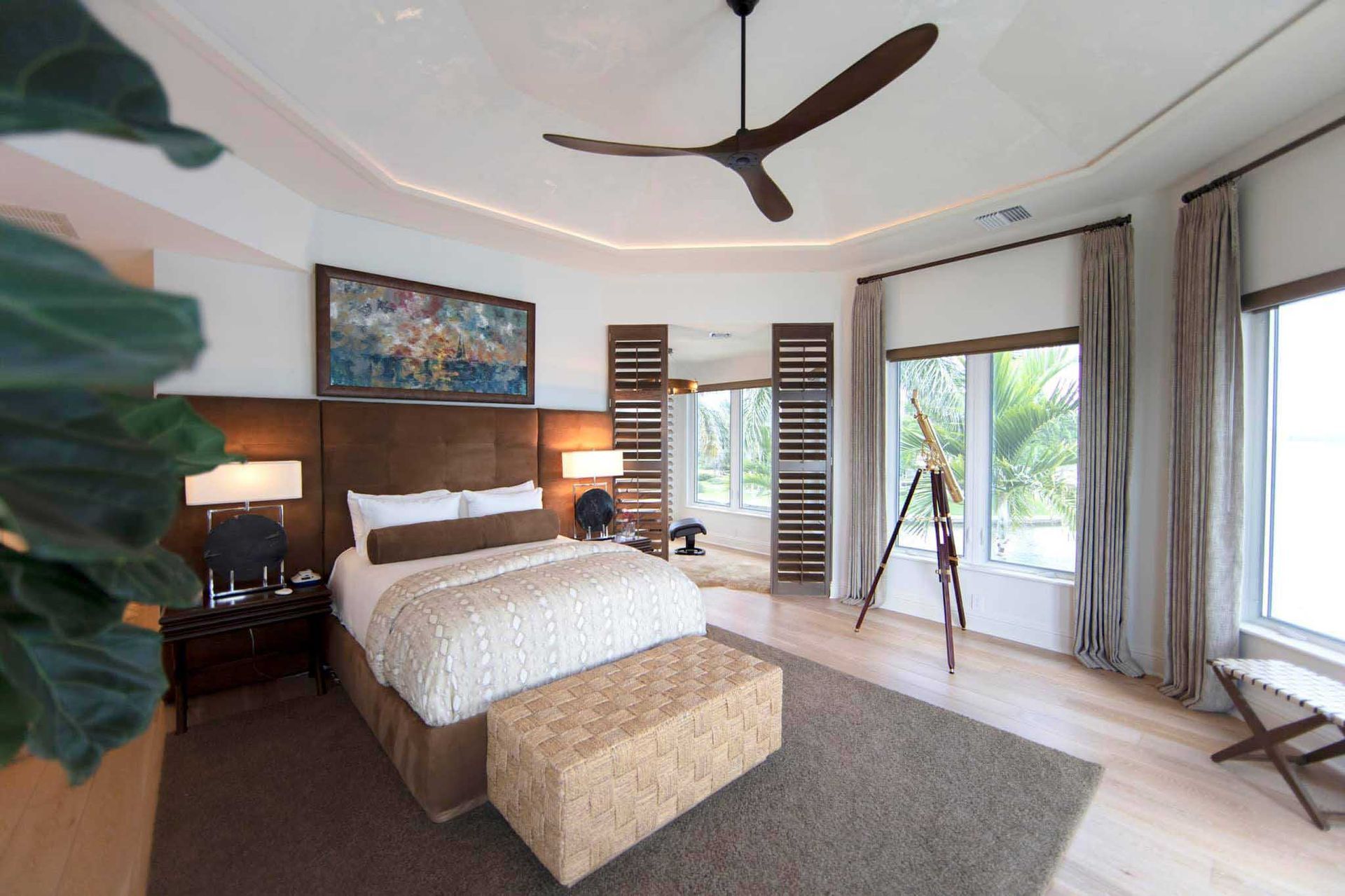Bedroom with king bed, brown accents, and large windows with outdoor view.