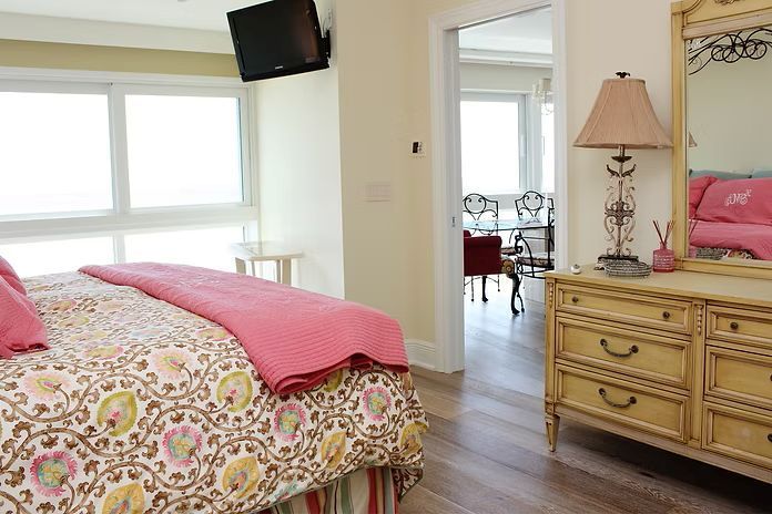 Bedroom with floral bedspread, dresser, and a glimpse into a dining area.