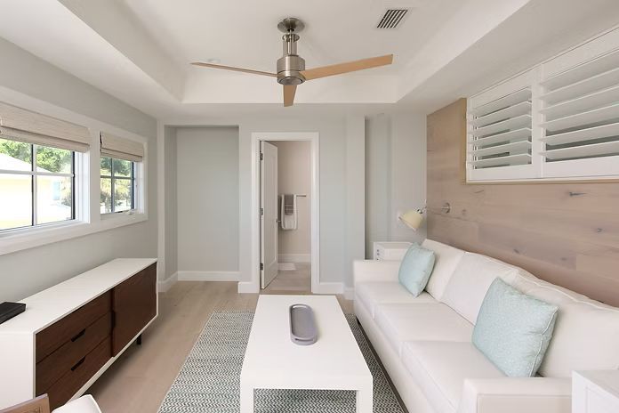 Living room with white sofa, coffee table, and wood accent wall. Light blue and white color scheme.