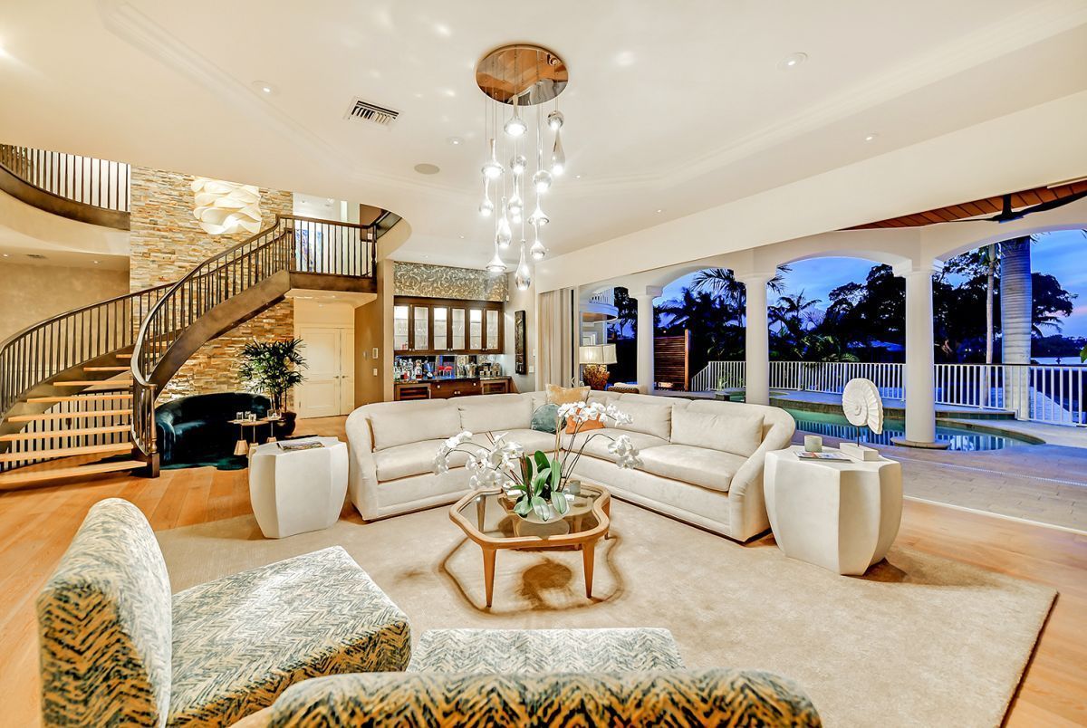 Spacious living room with spiral staircase, white sofas, patterned armchairs, and outdoor patio access.