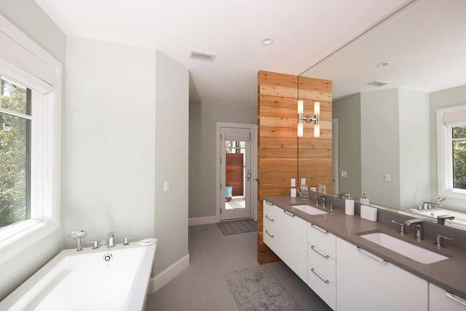 Modern bathroom with wood wall, double sink vanity, large mirror, and soaking tub.