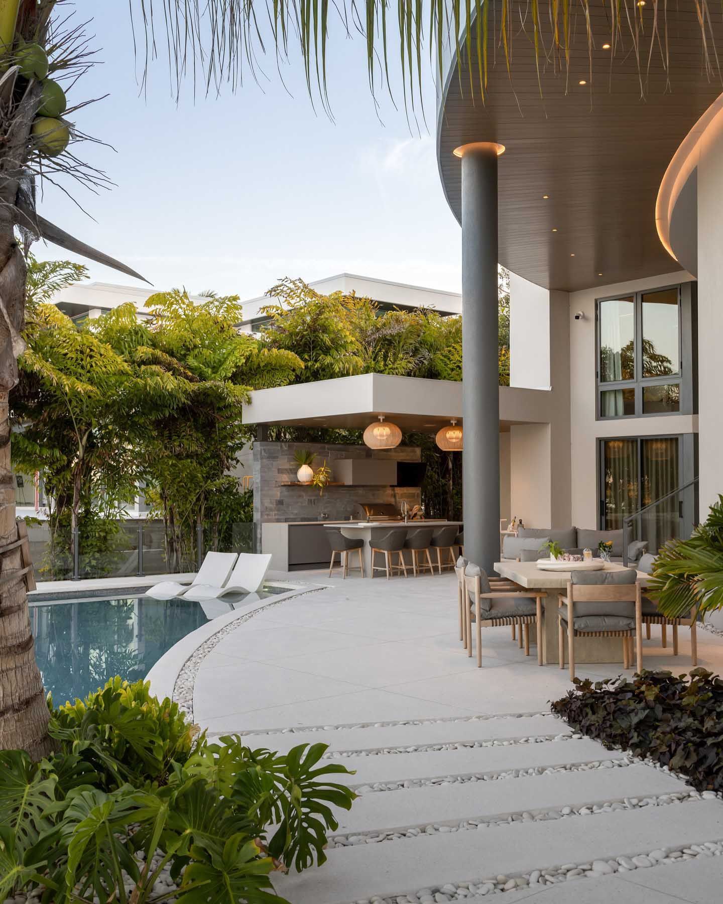 Outdoor patio with pool, dining, and kitchen areas, modern architecture.